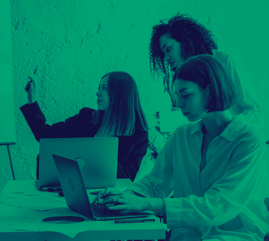 Mujeres trabajando en una oficina con computadora y un pizarrón, analizando resultados del blog de marca para su negocio que desean crecer y que kipit digital les ayuda.
