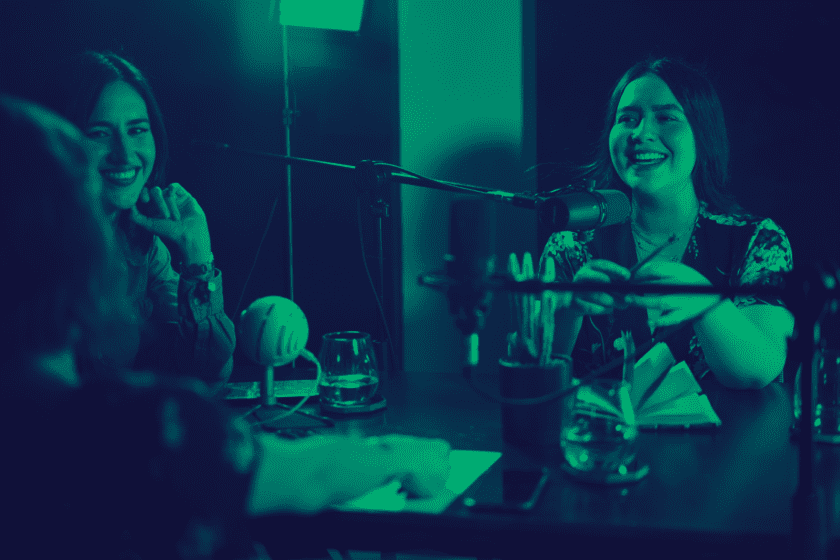 Tres mujeres al micrófono platicando y riéndose ilustran el artículo acerca de los tipos de podcast. Kipit Digital Agencia de Comunicación y Marketing Digital.